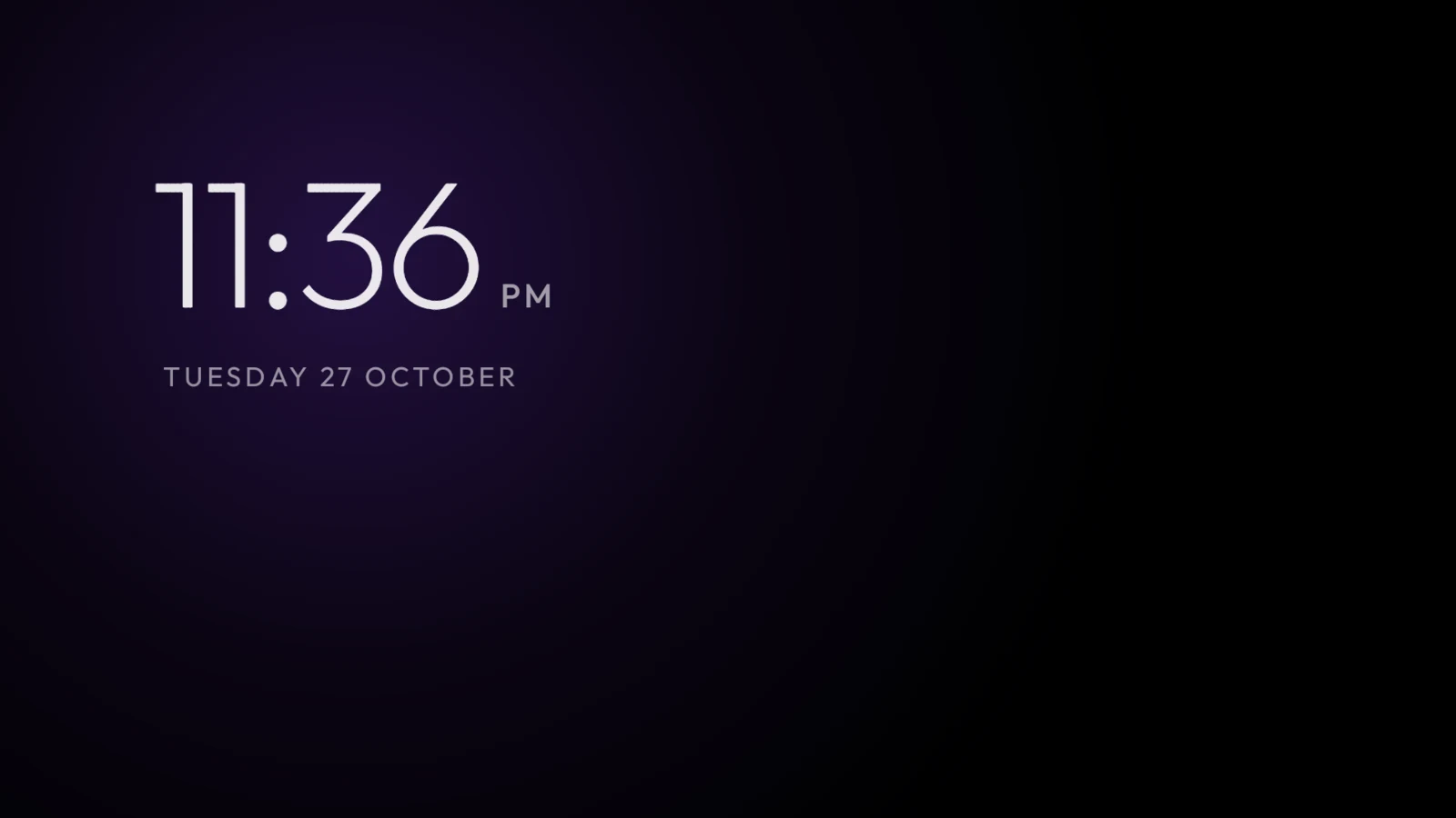 The default clock screensaver, showing the time and date over a dark background with a soft purple glow.